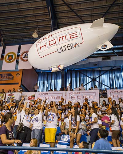 Fans cheer as the PLDT Home Ultera blimp flies over them in Game 3 of the Shakey’s V-League Open Conference finals at the FilOil Flying V Arena. 