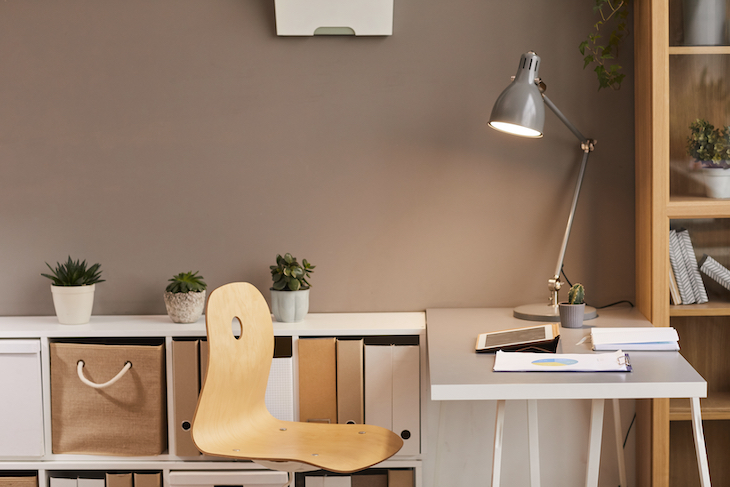 Cozy workplace lit by warm lighting from metal desk lamp