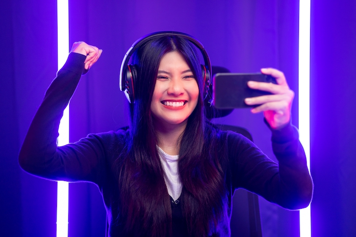 Female pro streamer wearing headphones playing game (1)
