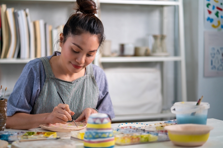 Woman learning and painting self-made pottery at home
