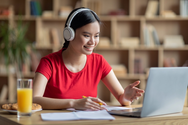 Young woman wearing wireless headphones working with laptop